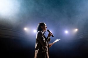 A picture of a woman giving a speech with a script.