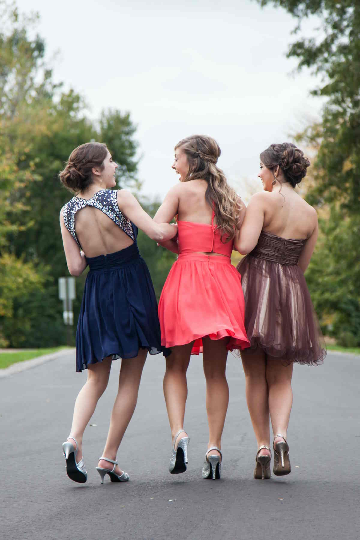 Rear shot of 3 girls laughing dressed up as they walk along the road representing Maid of Honour icebreakers